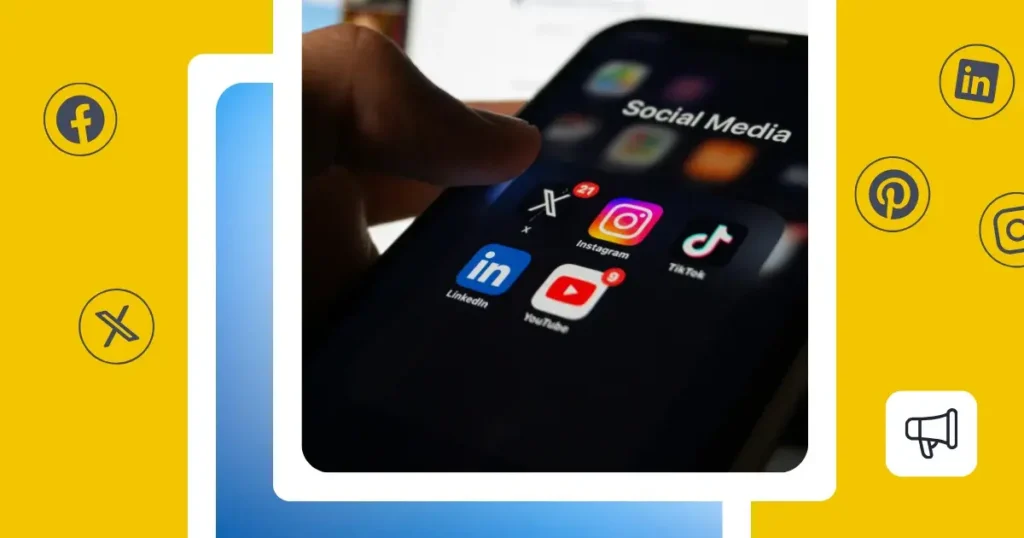 Close-up of a hand holding a smartphone displaying social media apps, including Instagram, TikTok, LinkedIn, YouTube, and X, with notification badges visible on the screen.