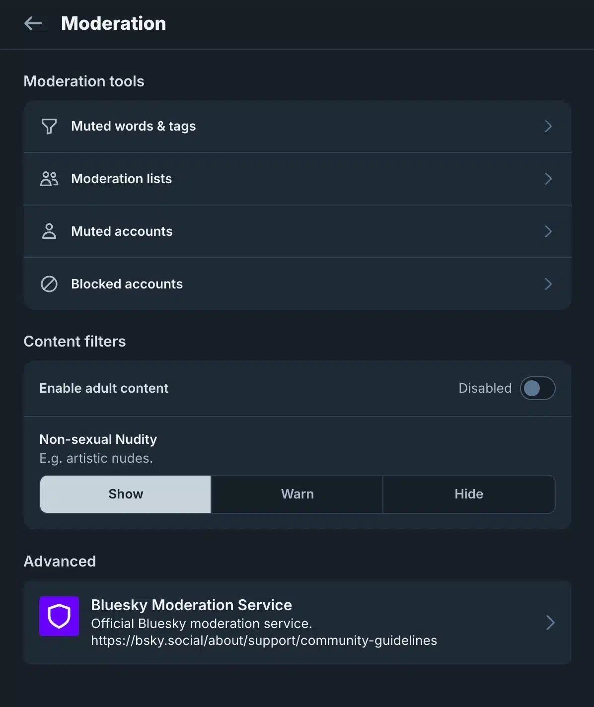 A dark-mode Bluesky “Moderation” settings screen. It lists moderation tools for muted words and tags, moderation lists, muted accounts, and blocked accounts. Under “Content filters,” adult content is disabled, and non-sexual nudity can be set to Show, Warn, or Hide, with Show selected. An “Advanced” section contains the Bluesky Moderation Service with a link to the community guidelines.