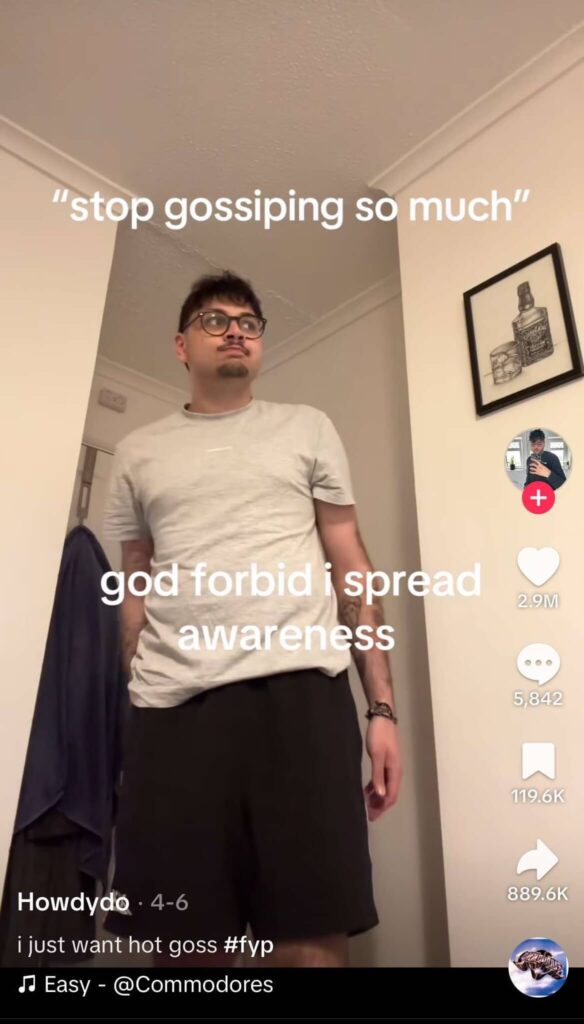 A person stands in a room with white walls and a framed picture, wearing a light gray t-shirt and black shorts. Text reads, 'stop gossiping so much' and 'god forbid i spread awareness,' indicating participation in a TikTok trend.