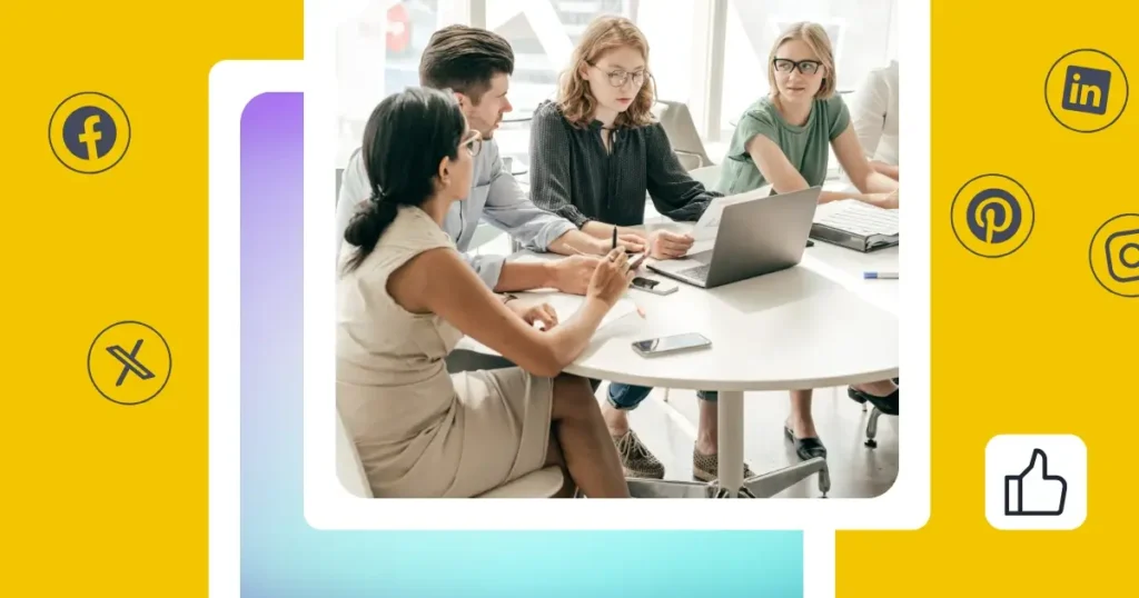 Group of professionals sitting around a white table in a bright office space, collaborating on a laptop