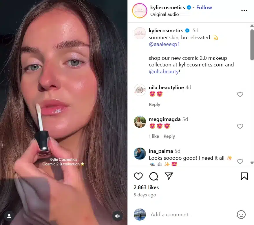 A close-up of a woman applying a Kylie Cosmetics lip gloss from the Cosmic 2.0 collection. The caption reads “summer skin, but elevated,” promoting the new product launch available online and at Ulta Beauty. 