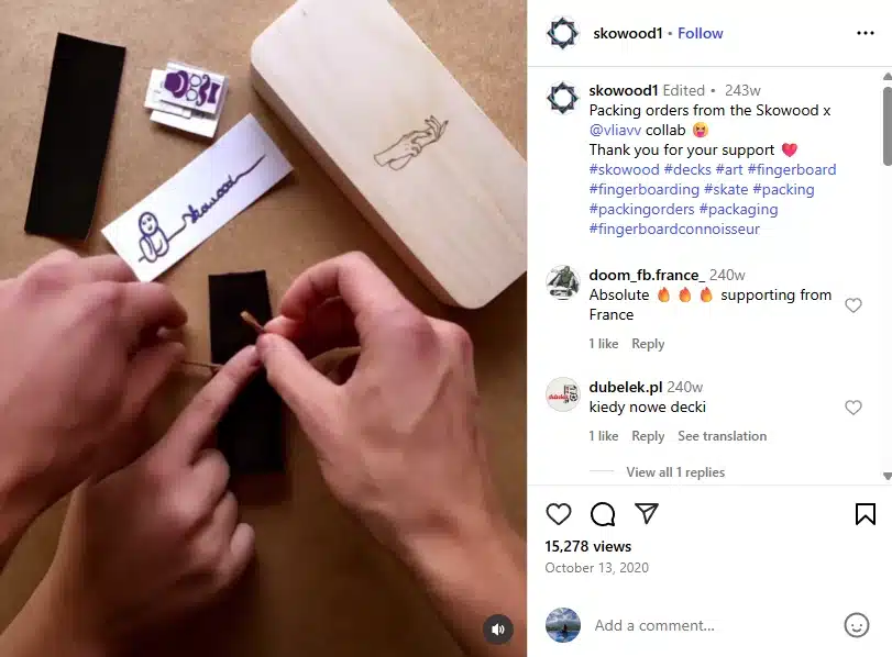 Hands assembling a fingerboard deck from Skowood’s collaboration with Viawv. The table features grip tape, custom stickers, and a wooden fingerboard box with an engraved hand logo.