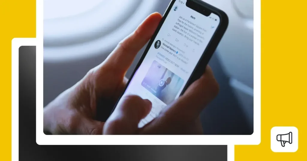 Close-up of hands holding a smartphone displaying the Twitter app with tweets and an embedded video.