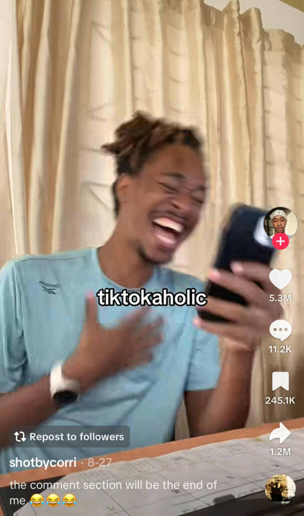 A man laughing while holding a phone with the caption ‘tiktokaholic’ across the screen.