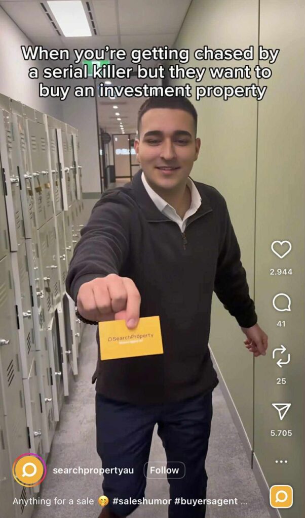 A man is standing in a hallway lined with lockers, holding out a bright yellow business card toward the camera. The card has text that appears to reference a property search service. At the top of the image, white text reads: “When you’re getting chased by a serial killer but they want to buy an investment property.”