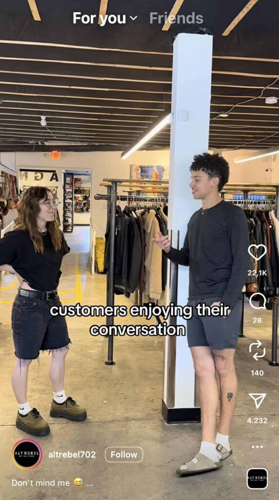 Two people stand inside a clothing store, talking near racks of clothes. Text on the image reads: “customers enjoying their conversation.”
