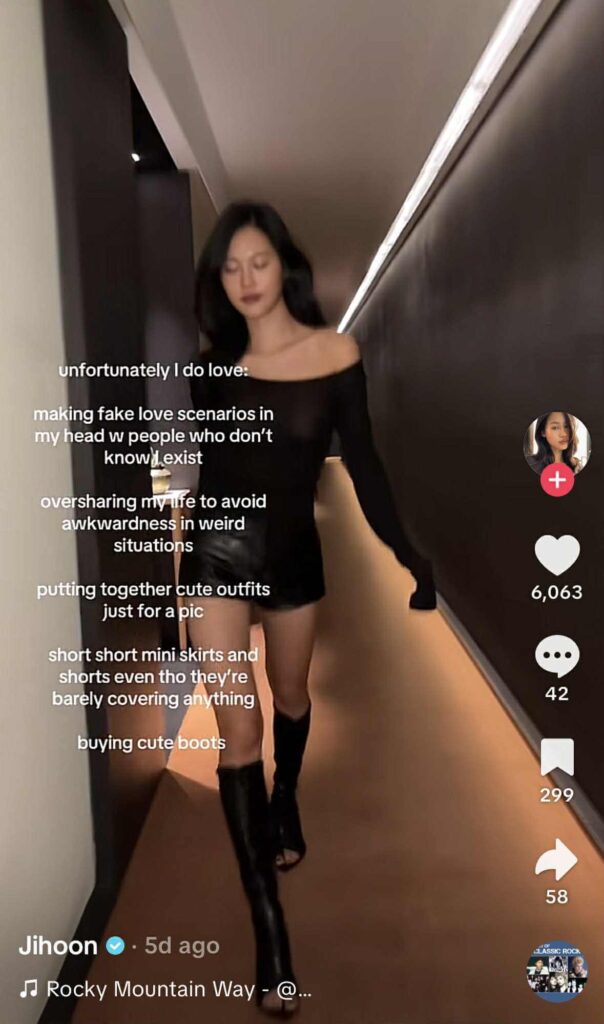 A woman wearing a black off-the-shoulder top, black shorts, and tall black boots walks down a narrow, dimly lit hallway. White overlay text lists humorous confessions beginning with “unfortunately I do love,” describing habits like imagining fake love scenarios and buying cute boots.