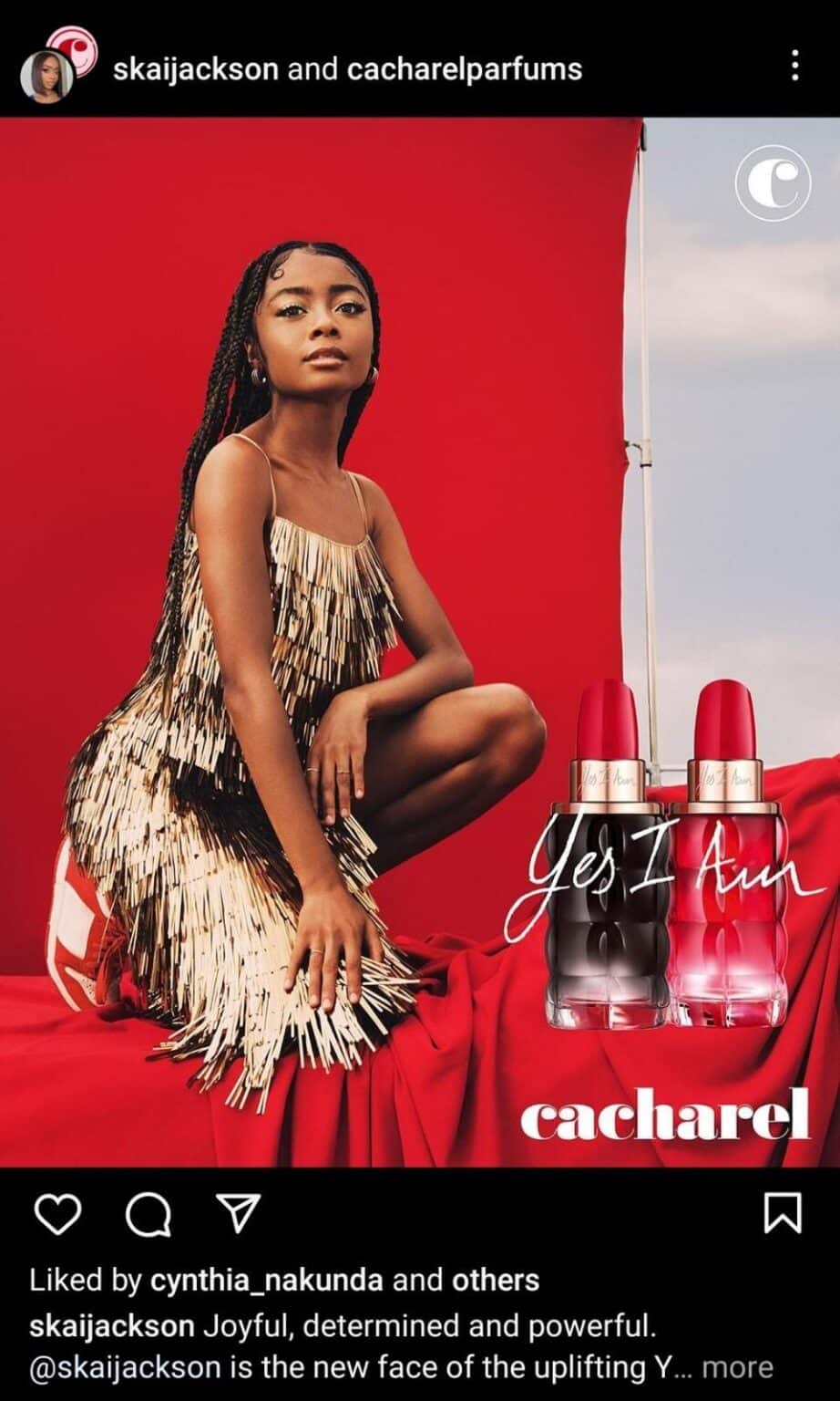 Instagram collaboration post featuring Skai Jackson posing confidently in a gold fringe dress against a red backdrop, promoting Cacharel’s “Yes I Am” perfume bottles displayed beside her.