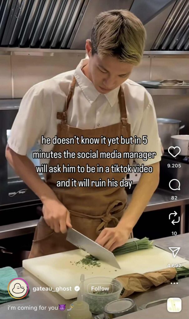 Instagram Reel of a chef in a white shirt and brown apron chopping herbs in a kitchen. The on-screen caption reads, “he doesn’t know it yet but in 5 minutes the social media manager will ask him to be in a tiktok video and it will ruin his day.”