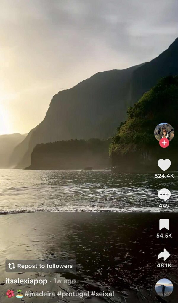A serene coastal view at sunset in Seixal, Madeira, Portugal, showing waves gently washing ashore with tall cliffs in the background under a golden sky.