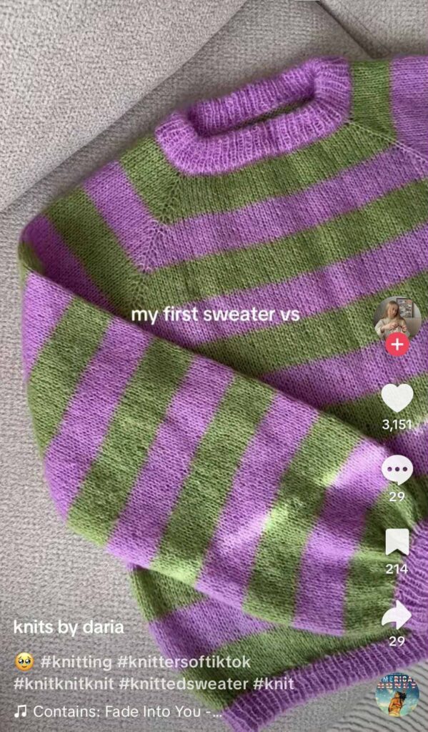 TikTok showing a hand-knitted sweater with purple and green horizontal stripes laid out on a gray fabric surface.