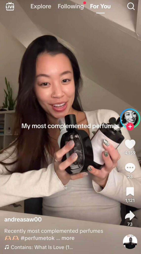 A woman smiling and holding several perfume bottles while sitting at a desk. The text on screen reads “My most complemented perfumes.”