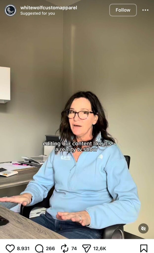 A woman wearing glasses sits at an office desk, gesturing with her hands, with on-screen text that reads, “editing our content like it’s a reality tv show.”
