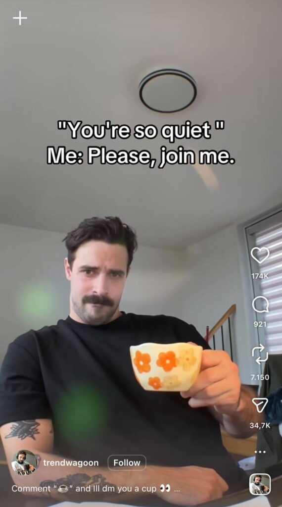 A man with a mustache holds a floral teacup toward the camera while staring seriously. On-screen text reads, “You’re so quiet. Me: Please, join me.”