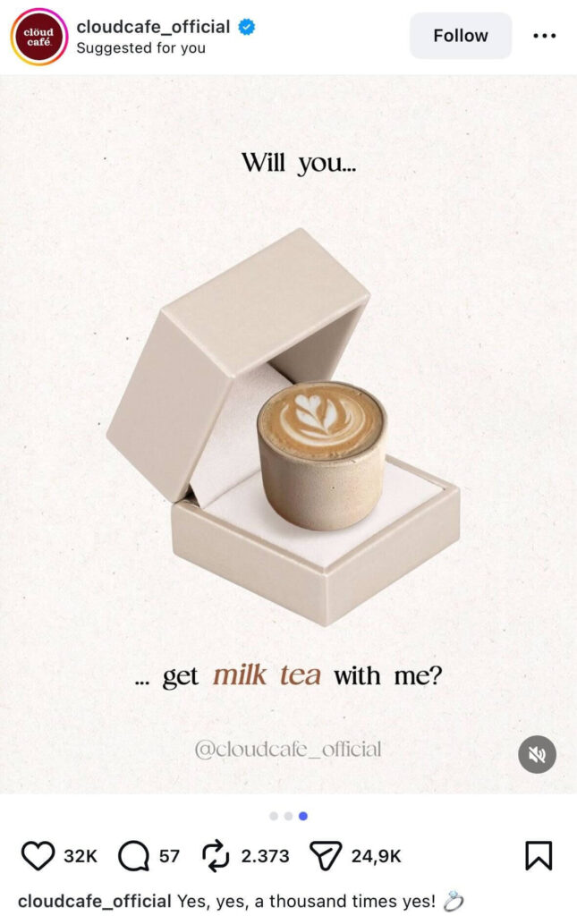 A ceramic cup of milk tea with latte art sits inside an open ring box on a neutral background, with text reading, “Will you… get milk tea with me?”