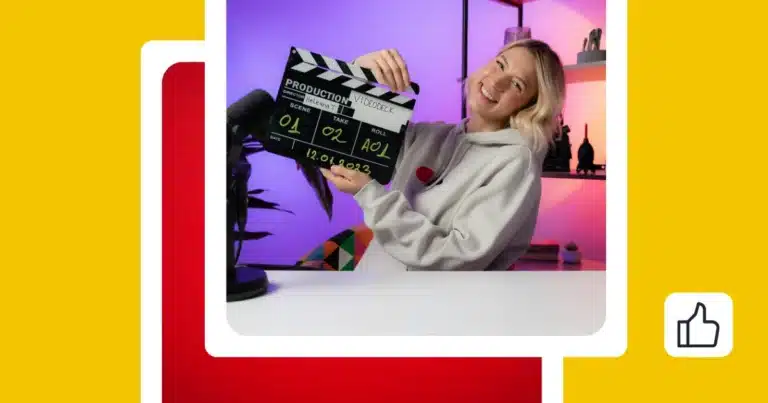 Smiling female content creator in a home studio holding a film clapperboard next to a microphone, with colorful lighting in the background.