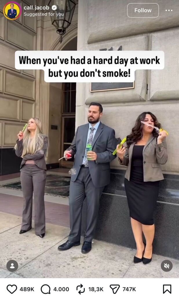 Three office workers in business attire stand outside a building blowing bubbles, with on-screen text about having a hard day at work but not smoking.
