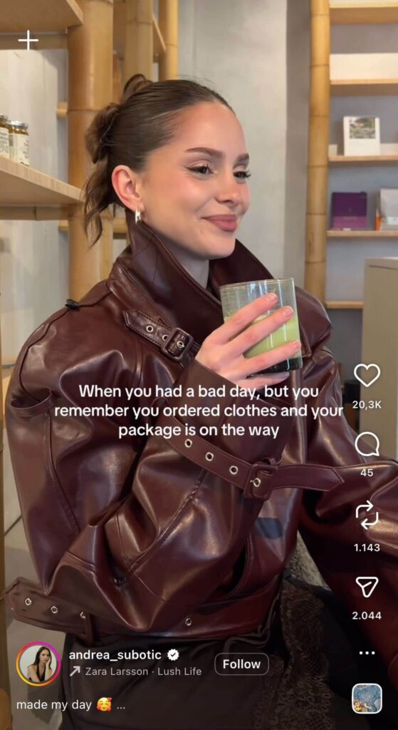 A woman in a café wearing a brown leather jacket smiles while holding a green drink, with on-screen text about having a bad day but remembering an online shopping order is on the way.