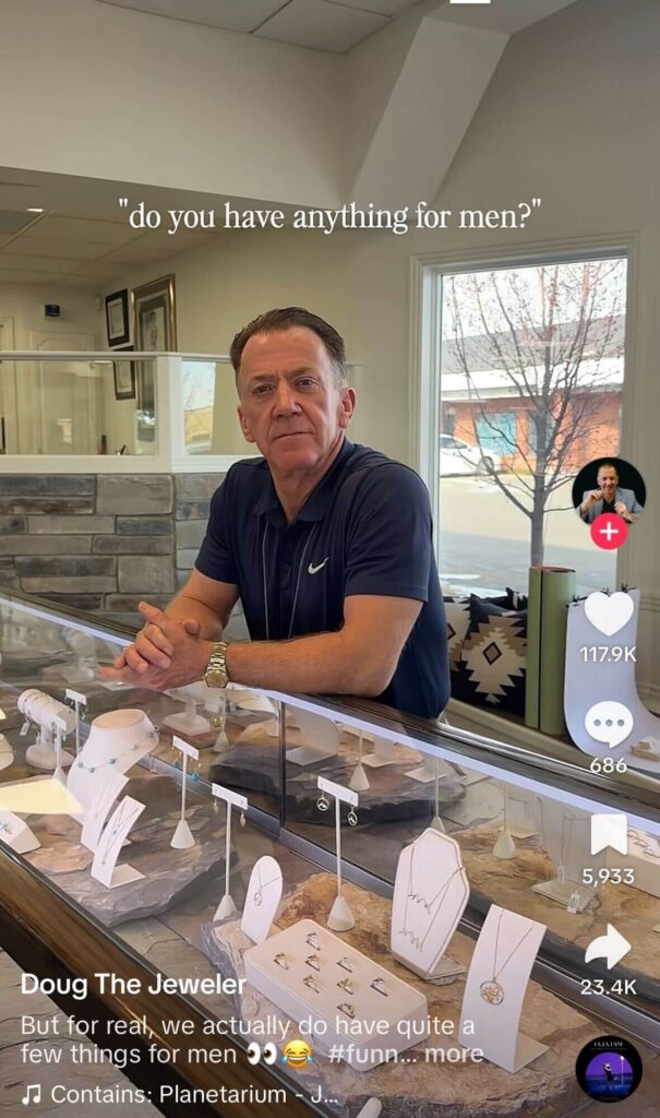 Man standing behind a jewelry store counter with display cases of necklaces and rings, with text overlay reading “do you have anything for men?” in a TikTok video.