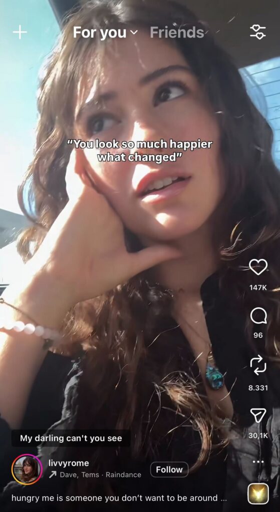 Woman sitting in a car with sunlight on her face and text overlay “You look so much happier what changed” in an Instagram Reel