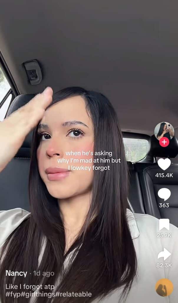 A woman sitting in a car looking slightly frustrated, with text joking about forgetting why she was mad during an argument.
