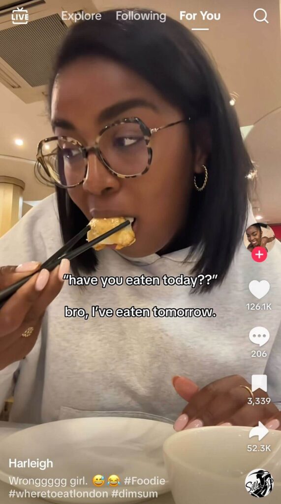 Woman wearing glasses eating dumpling with chopsticks in a restaurant; overlaid text reads “have you eaten today?? bro, I’ve eaten tomorrow.”
