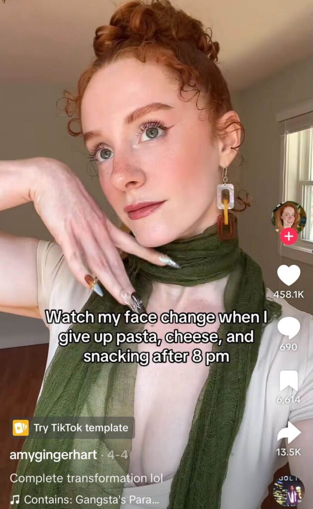 Red-haired woman with freckles posing indoors while wearing a green scarf and large earrings; overlaid text reads “Watch my face change when I give up pasta, cheese, and snacking after 8 pm.”