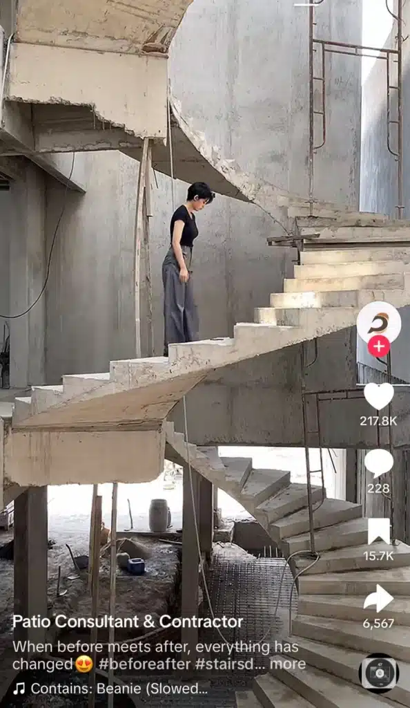 TikTok video showing a person walking through unfinished concrete staircases inside a raw construction site during a renovation project.