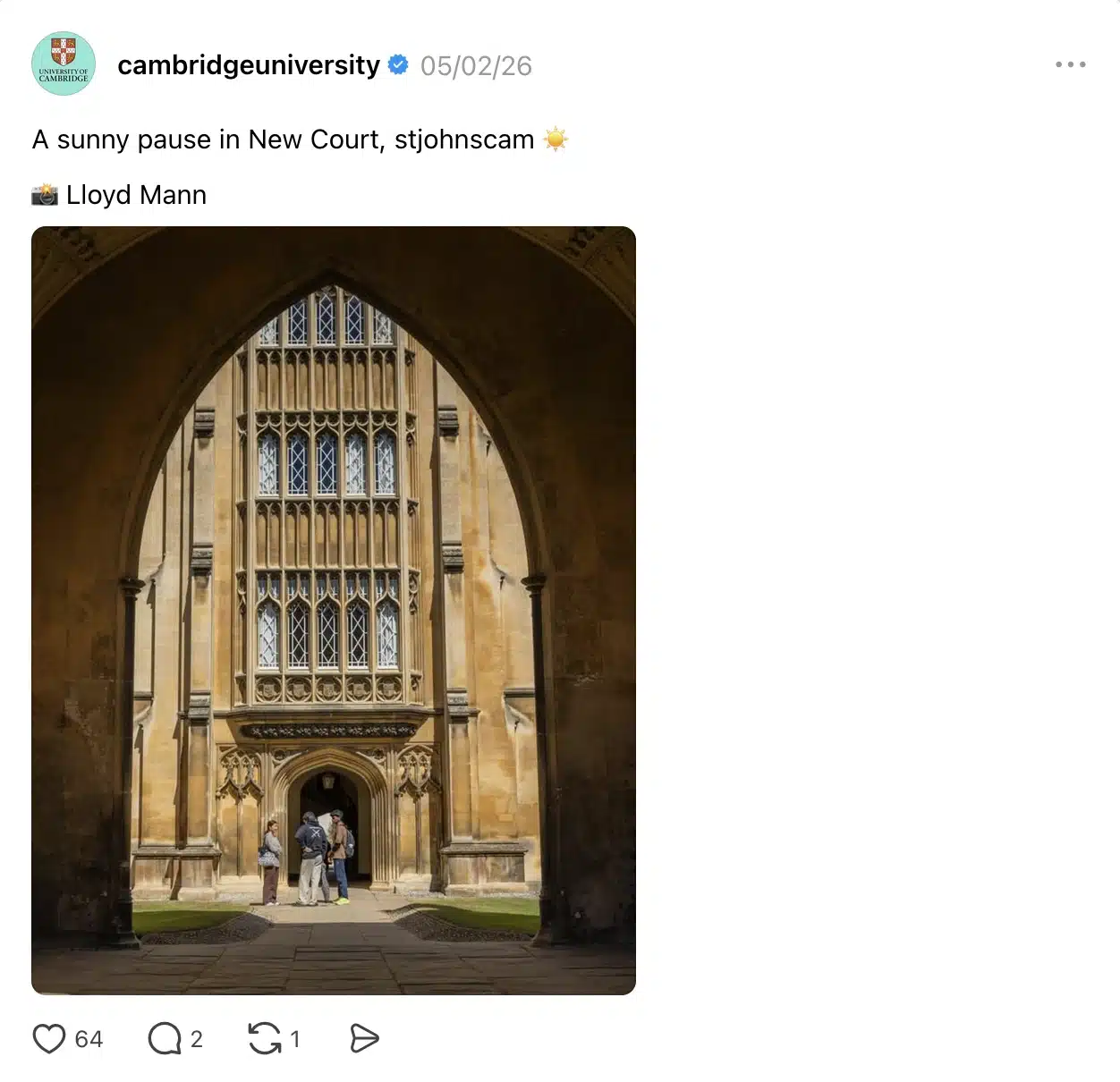 Social media post from the University of Cambridge showing a sunlit view through a large stone archway into New Court at St John’s College. Three people stand near the entrance of the historic Gothic-style building, with tall ornate windows and warm sunlight illuminating the courtyard scene.
