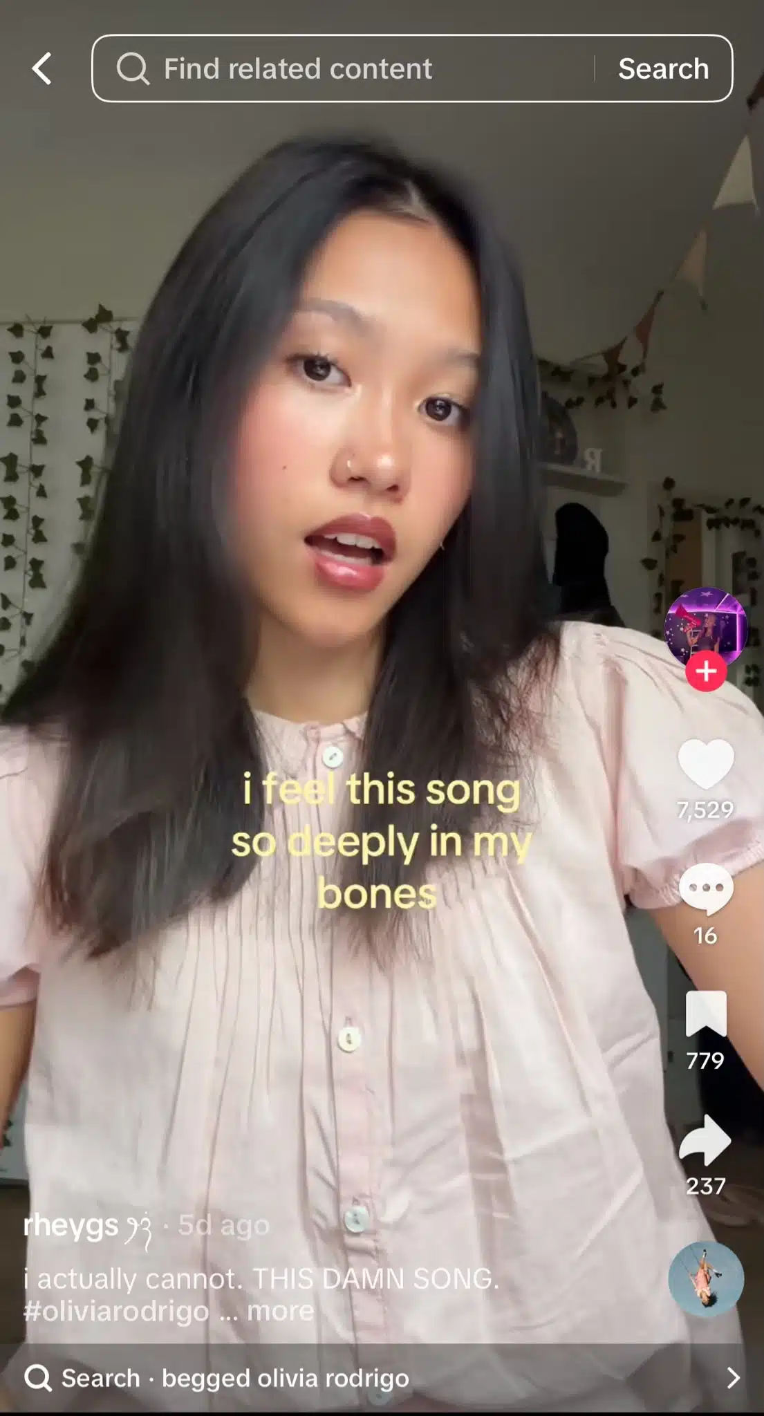 TikTok video from @rheygs showing a woman with dark hair wearing a light pink blouse, with on-screen text reading “i feel this song so deeply in my bones” and the TikTok interface displaying engagement metrics and search term “begged olivia rodrigo.”