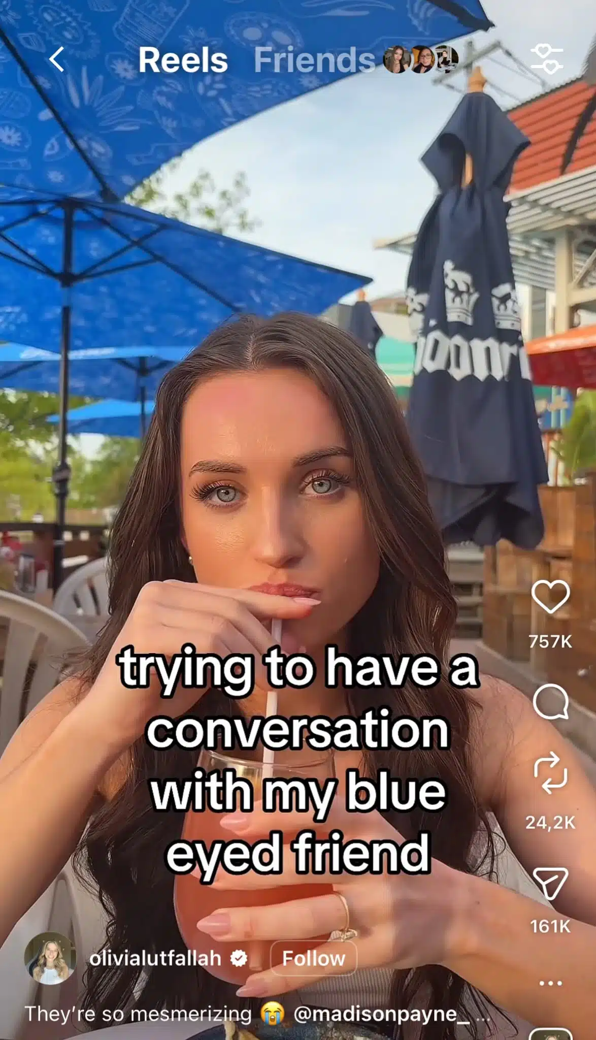 Instagram Reel from @olivialutfallah showing a woman drinking through a straw at an outdoor restaurant, with on-screen text reading “trying to have a conversation with my blue eyed friend” and the Reel interface displaying engagement metrics and follow button.