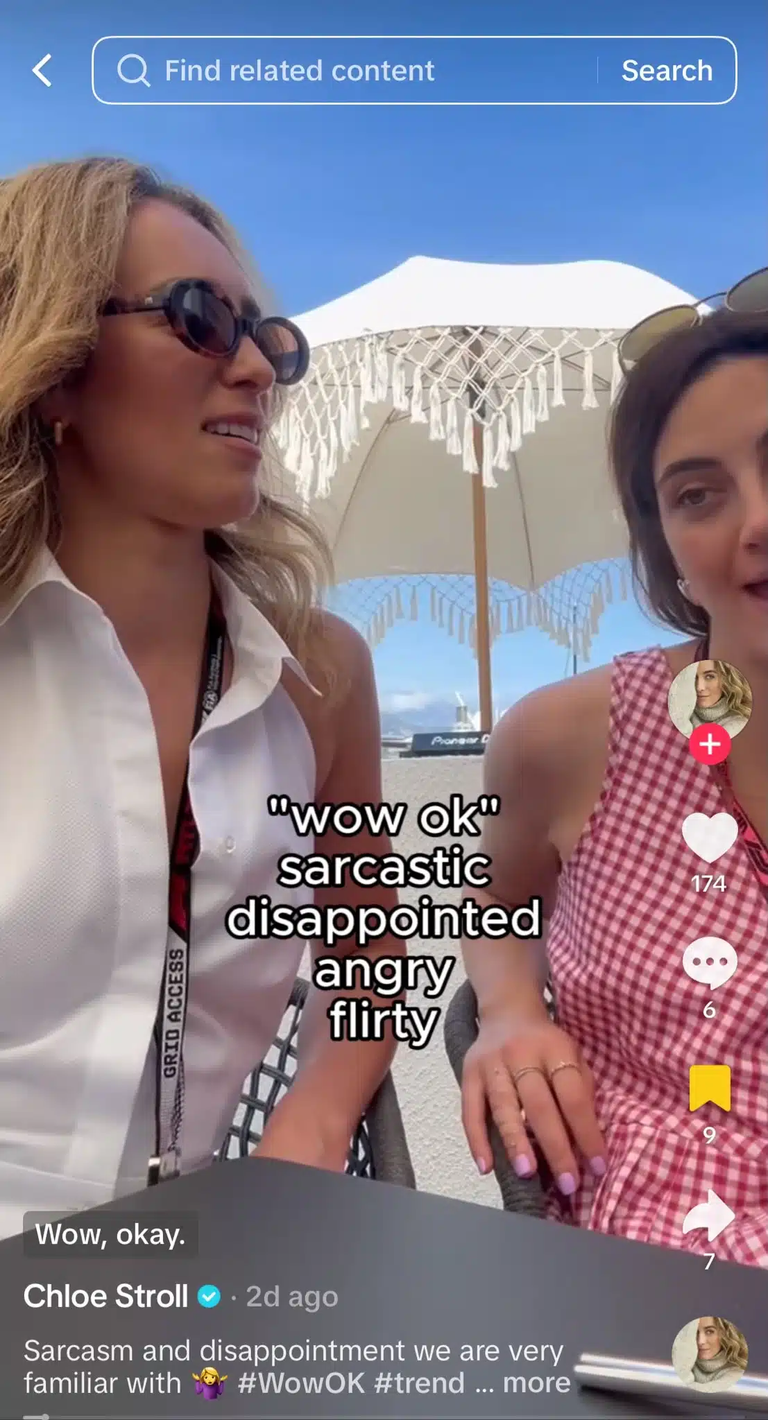Two women sit at an outdoor table beneath a white fringed umbrella on a sunny day. One wears sunglasses and a sleeveless white top, while the other wears a pink gingham dress. Overlay text reads, “wow ok” followed by “sarcastic,” “disappointed,” “angry,” and “flirty.”