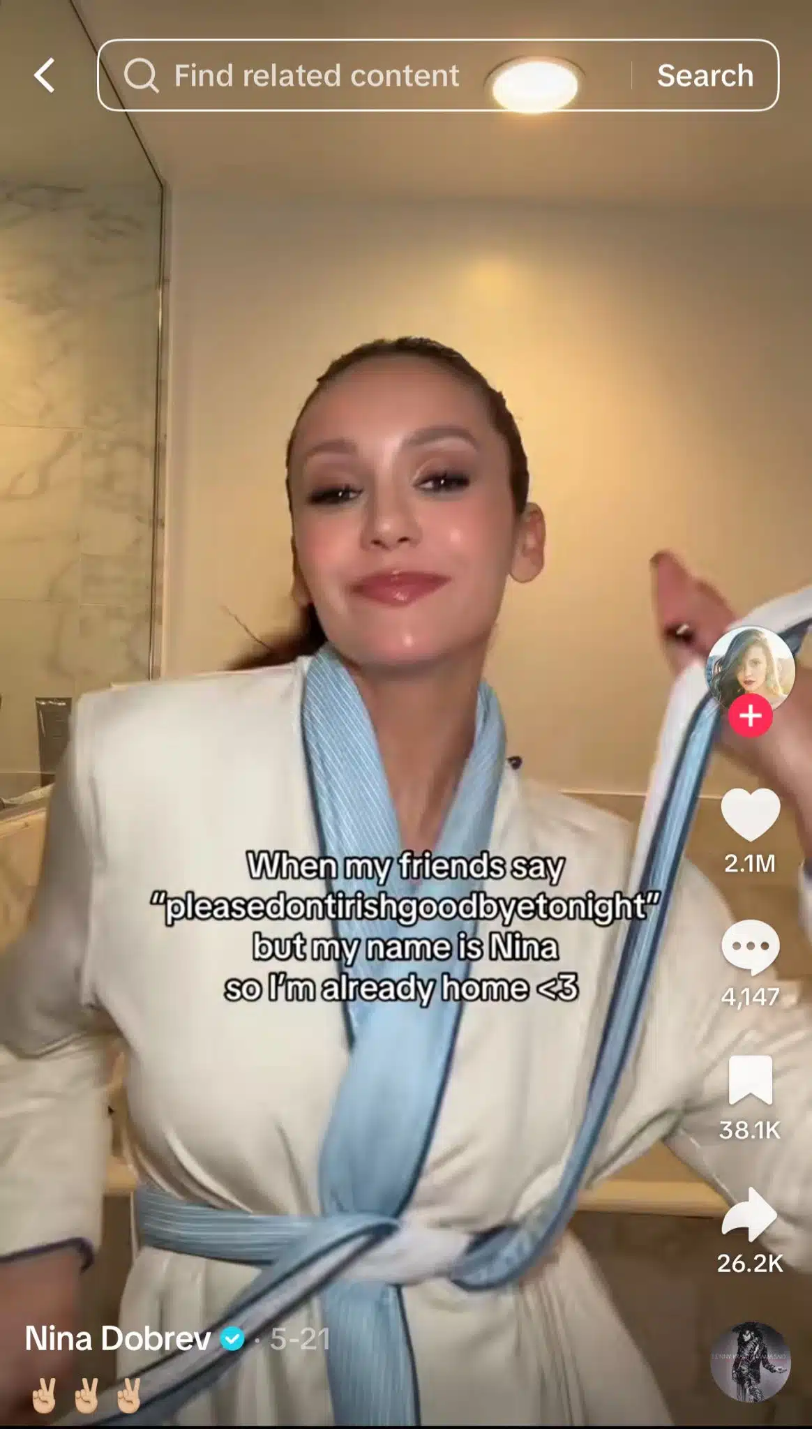 A woman in a white robe with blue trim stands in a bathroom, smiling and gesturing toward the camera. The background includes a shower enclosure and warm indoor lighting. White overlay text reads, “When my friends say ‘please dont irish goodbye tonight’ but my name is Nina so I’m already home <3.” TikTok interface elements are visible on the right side.