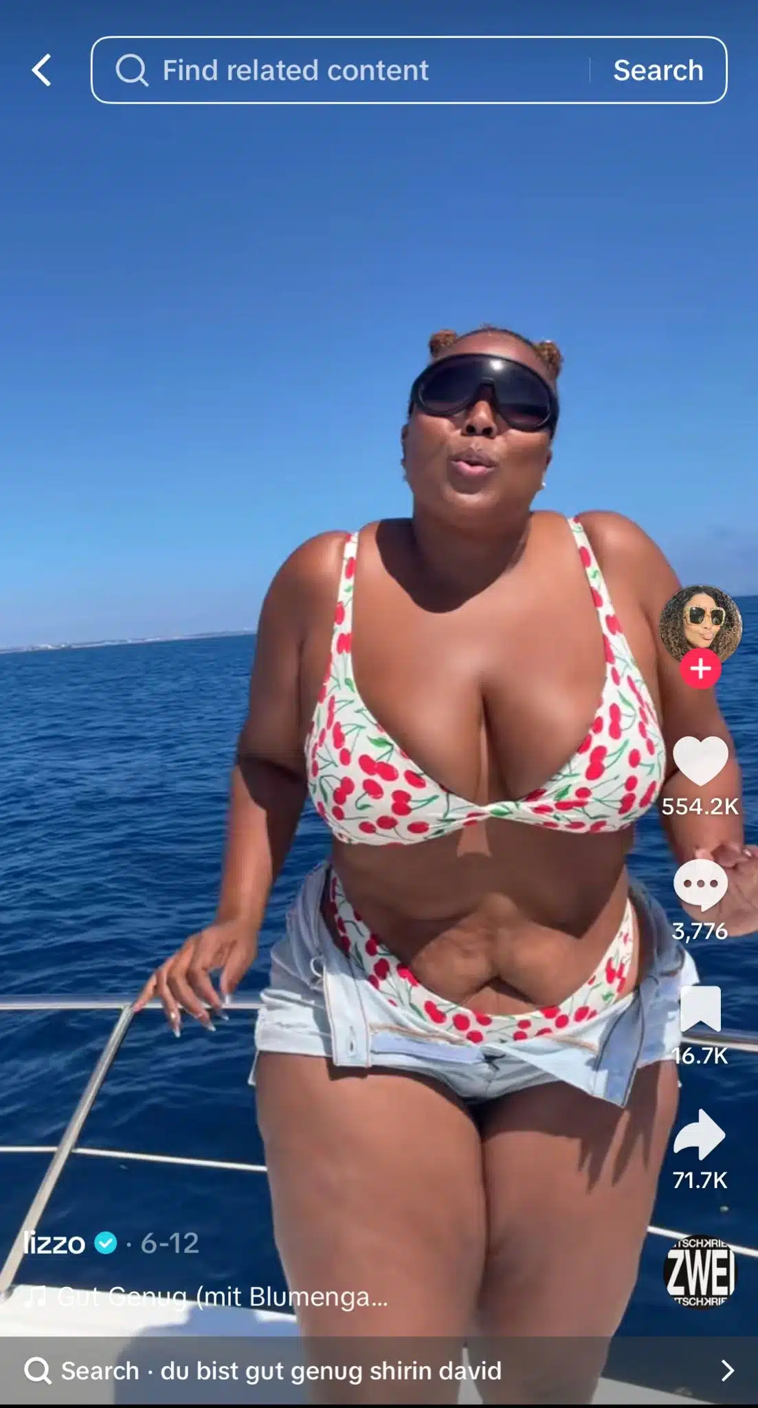 Person standing on a boat in the ocean wearing a cherry-print bikini and sunglasses, with blue water and clear sky in the background. TikTok interface is visible.