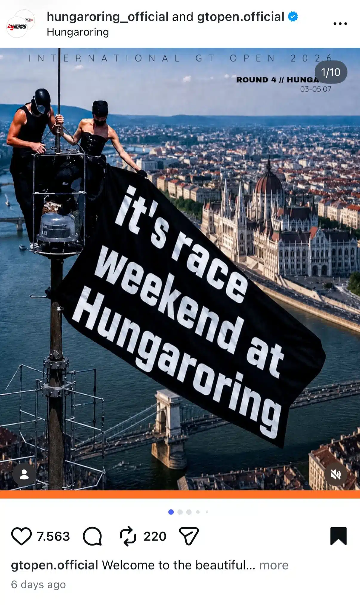 Instagram collaboration post from Hungaroring and GT Open announcing the race weekend. The image shows two people standing on top of a tall structure above Budapest, holding a large black flag reading "it's race weekend at Hungaroring," with the Hungarian Parliament and Danube River visible in the background.