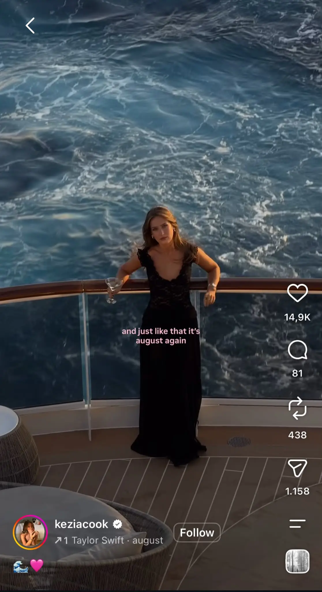 Instagram Reel featuring a creator standing on the deck of a cruise ship in a long black dress while holding a drink, with the ocean filling the background. Pink text over the video reads "and just like that it's august again." The Reel uses Taylor Swift's "august" audio and includes the standard Instagram interface with like, comment, share, and save icons on the right, plus the creator's username, follow button, and audio information at the bottom.