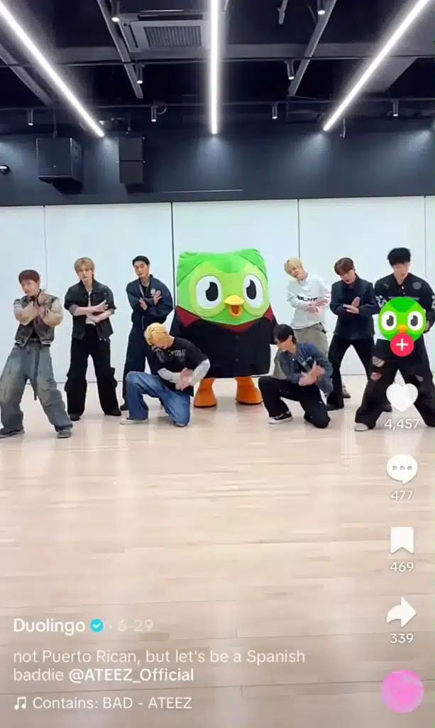 Duolingo mascot dancing with a K-pop group in a TikTok video, highlighting the brand's participation in viral trends.
