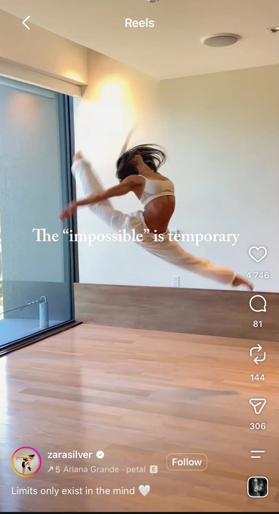 Instagram Reel capturing a dancer performing a high split leap in a minimalist studio with wooden floors and large windows. White overlay text reads 'The "impossible" is temporary.' The Reel uses Ariana Grande's "petal" audio and displays the standard Instagram interface with engagement icons on the right, while the creator's username, follow button, caption, and audio details appear at the bottom.