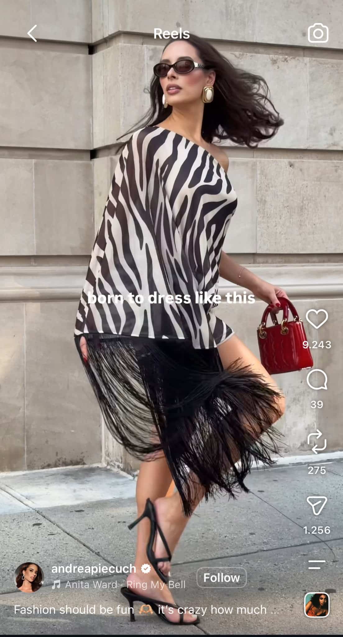 Instagram Reel from @andreapiecuch showing a woman posing in a black-and-white zebra-print outfit with sunglasses and a red handbag, with the text “born to dress like this.”