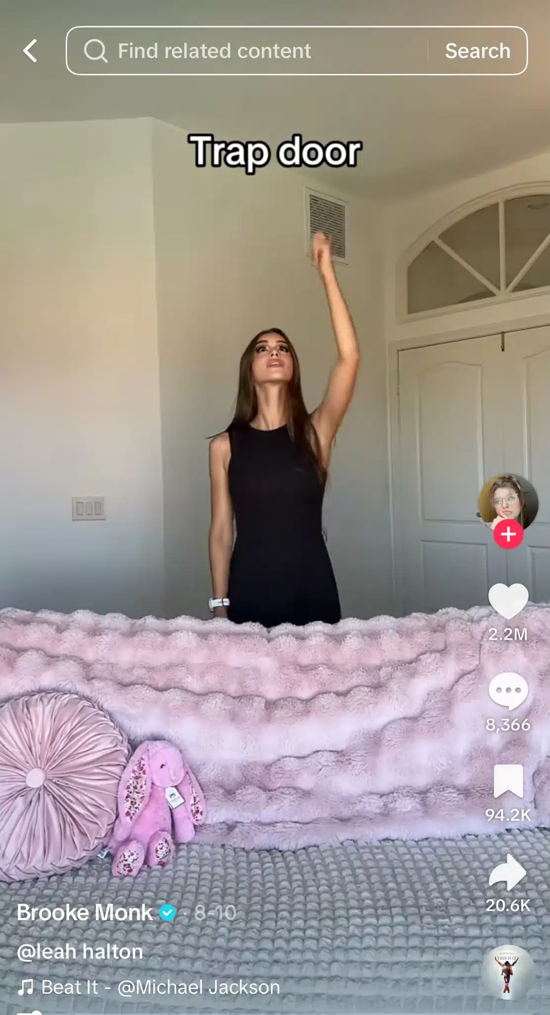 TikTok from Brooke Monk showing a woman standing behind a bed and pointing upward, with the text “Trap door” above her.