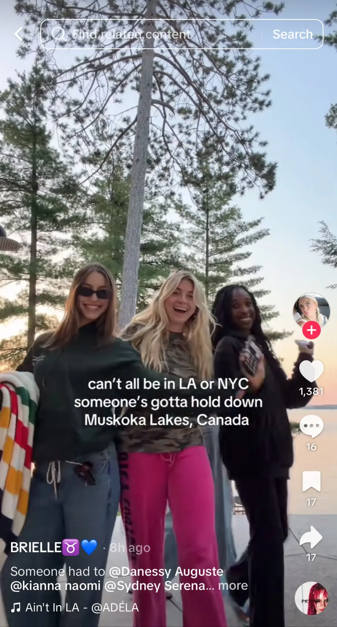 TikTok featuring three friends dancing outdoors at sunset by a lakeside. White text reads: "can't all be in LA or NYC someone's gotta hold down Muskoka Lakes, Canada." This trend humorously celebrates places outside major cities by suggesting that while many people aspire to live in popular destinations like Los Angeles or New York City, someone has to represent their hometown or region. The format uses location-specific text that creators customize to showcase where they're from, alongside the standard TikTok interface with engagement icons, creator details, and trending audio.