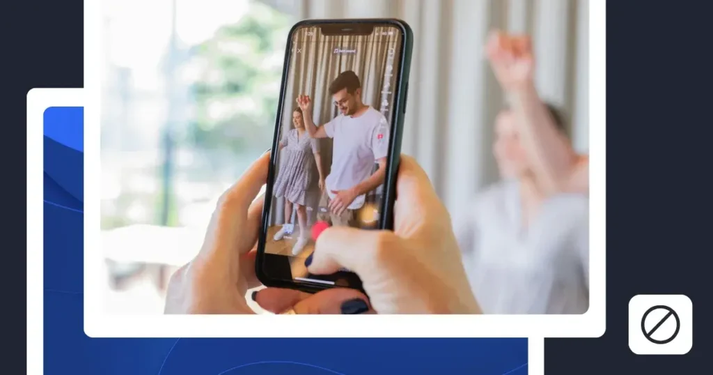A hand holding a smartphone displaying a TikTok video, with a person dancing on screen and a blurred person in the background. A blocked or restricted symbol appears beside the image.